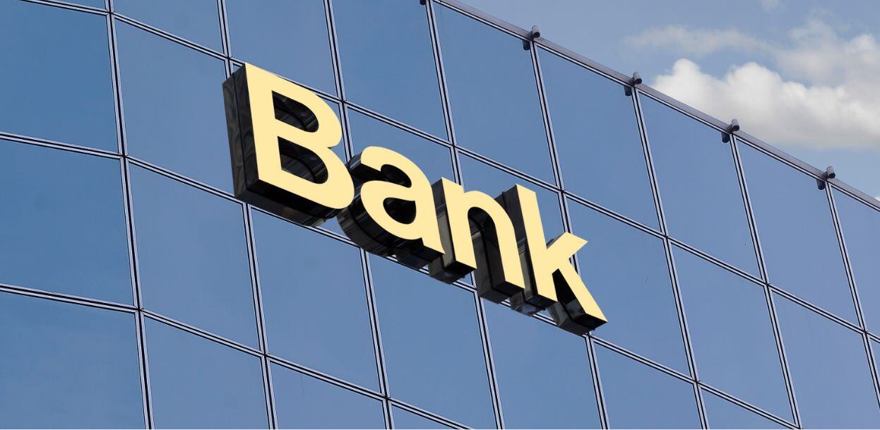 Dimensional letters of the word Bank appear on the side of a glass building