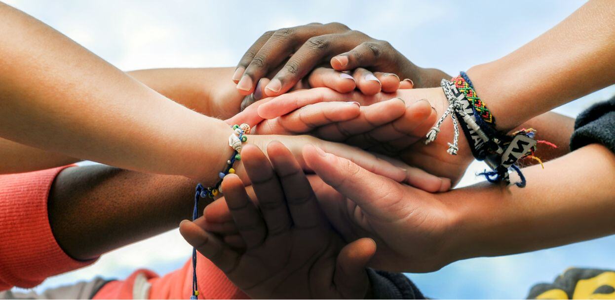 Several hands clutched together in a show of multi-cultural solidarity.